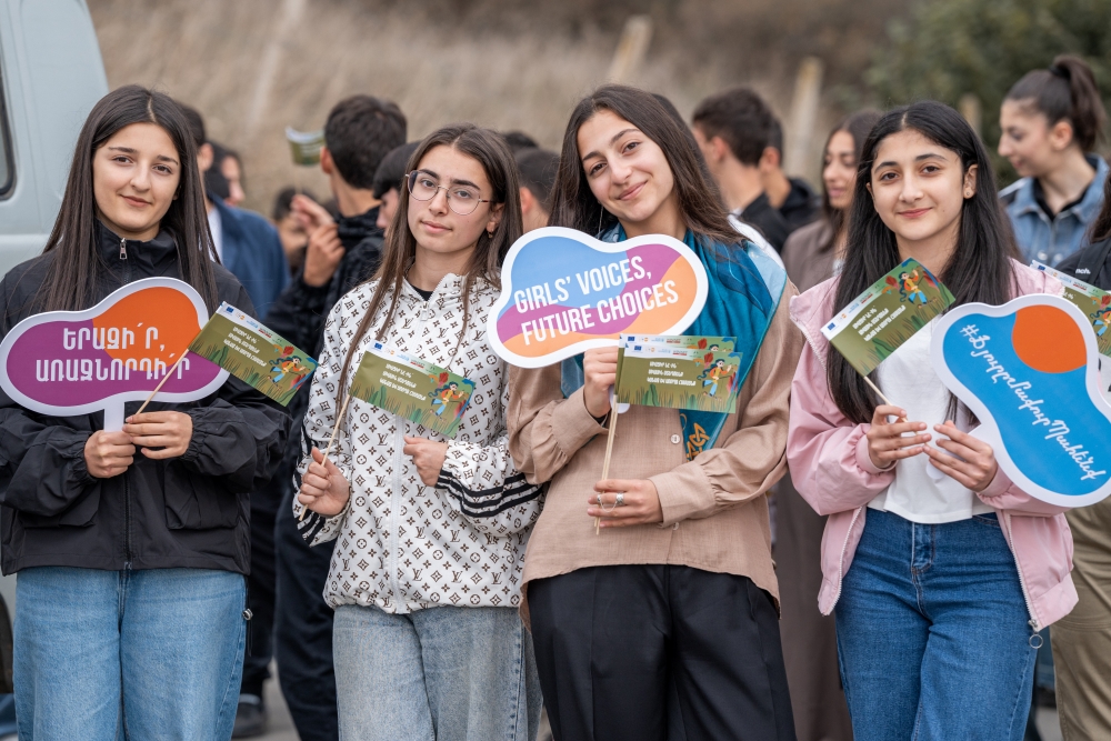 A group of young people walking and holding signs that read "Girls' Voices, Future Choices.