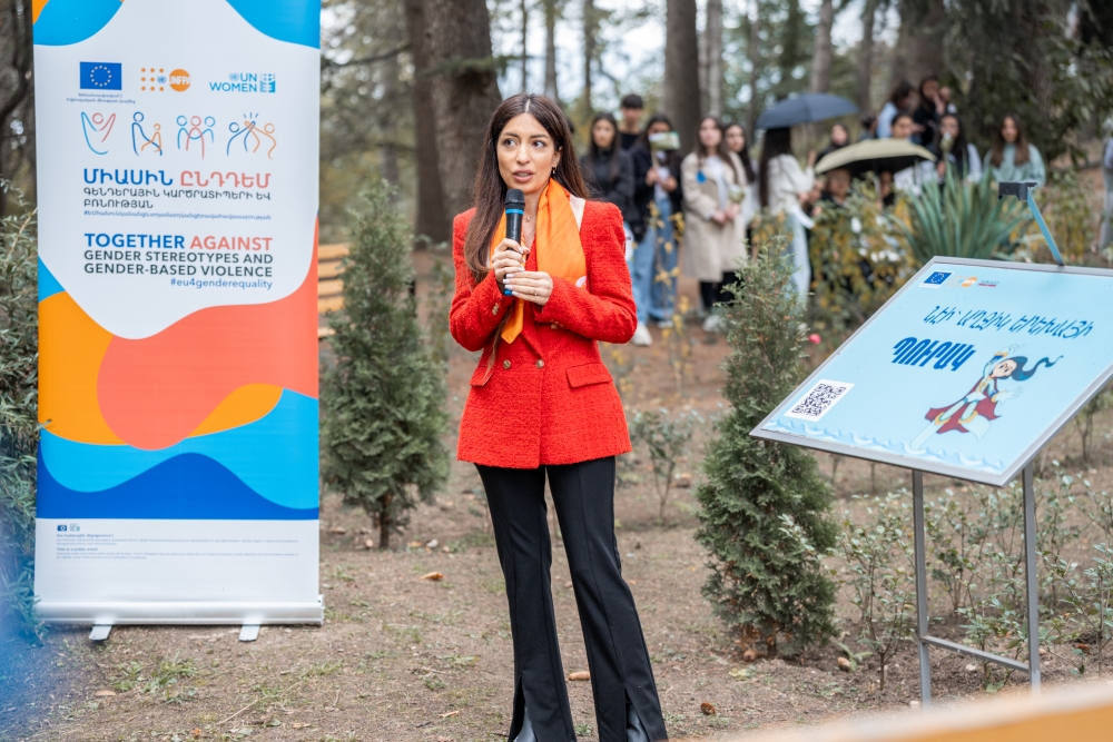 Person speaking at an outdoor event in front of the  “EU 4 Gender Equality: Together against gender stereotypes and gender-based violence” programme banner.