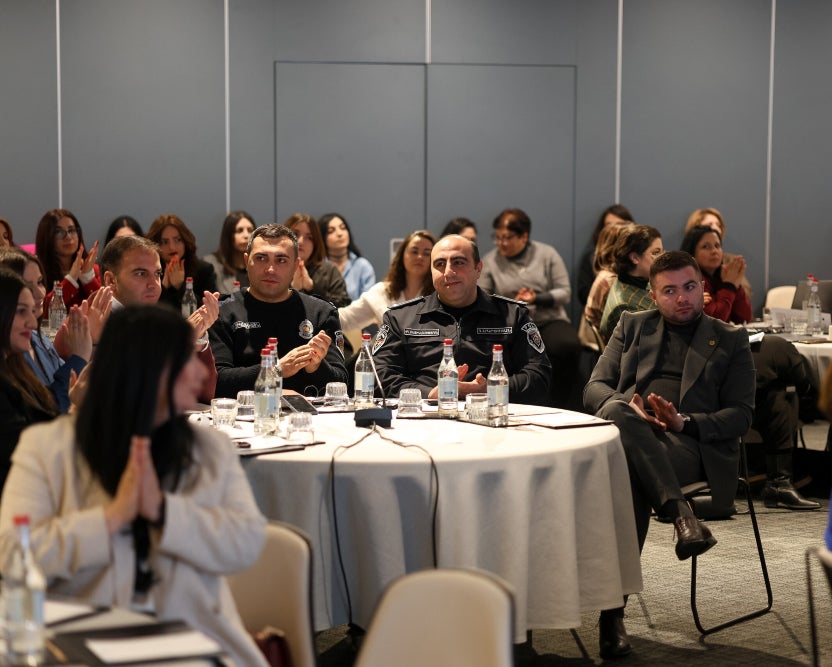 Audience members seated at a conference, listening attentively.