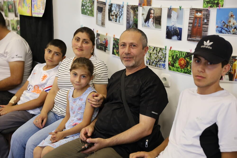 A father, mother, two boys, and a girl, a large family, participated in the event on family values, sitting together and smiling.