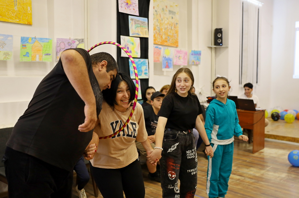 A family, participating in a game that promotes cooperation between family members. Mother, father, and two daughters play holding each other's hands.