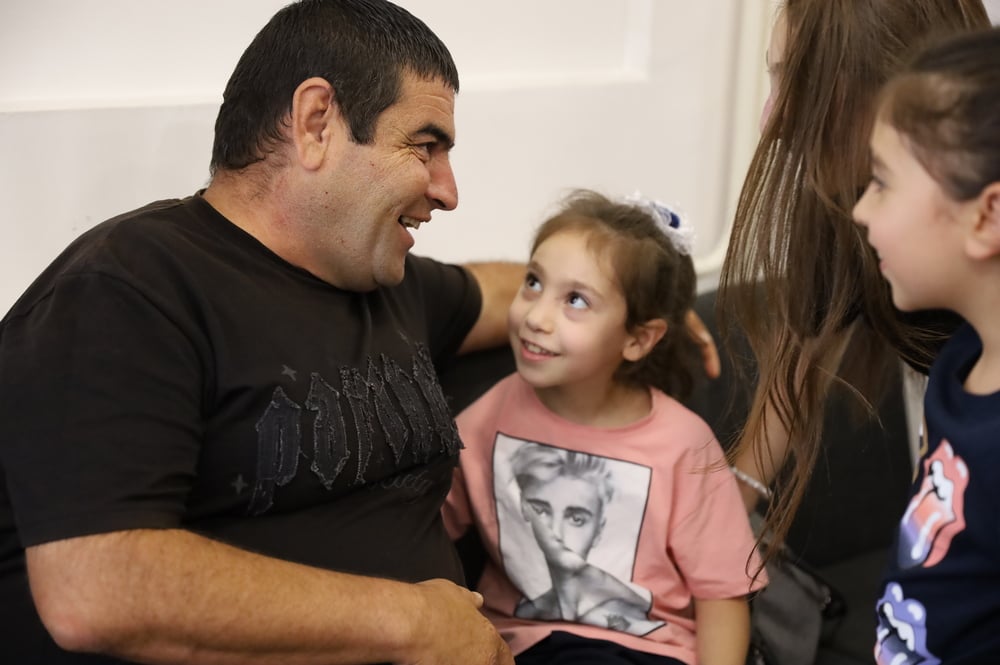 A father and daughter sitting together, smiling at each other.