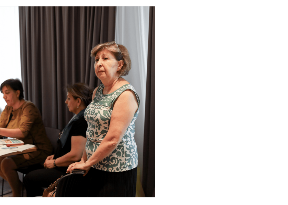 A woman standing in the meeting room and attentively looking to the left side 