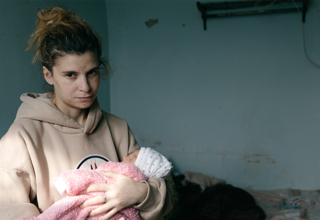 Marta Asriyan, holding her newborn, fifth in the family, whom she gave birth after fleeing to Armenia 