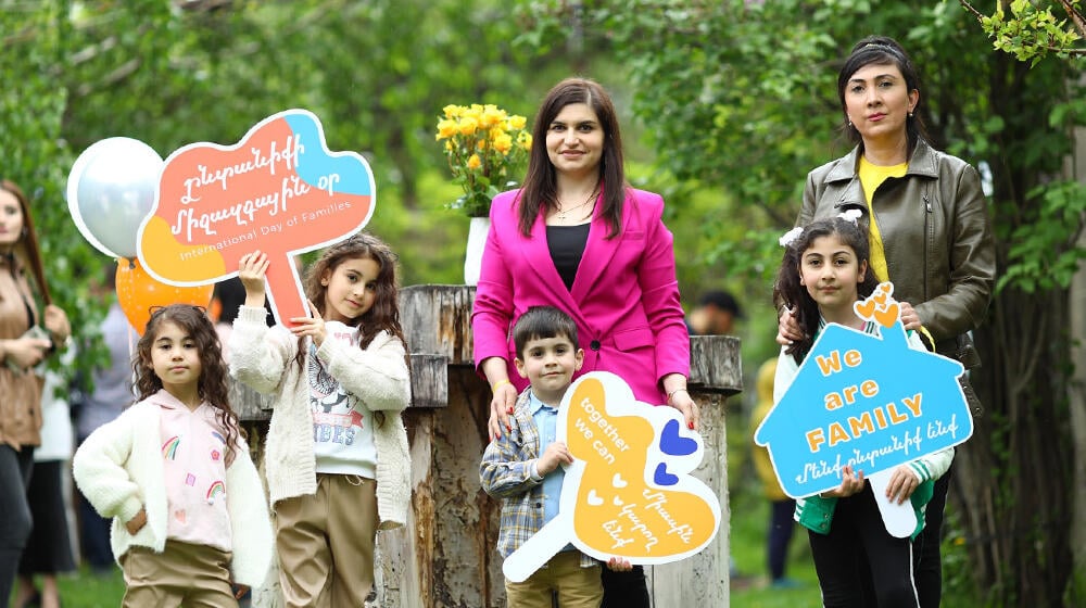 Two women and four children stand together, smiling, during the International Day of Families event. 